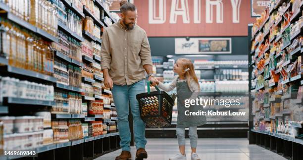 girl, father and grocery shopping with basket in shop for food, products or groceries in store. sales deals, family discount and man walking with kid or child in retail supermarket for buying goods. - shopping basket bildbanksfoton och bilder