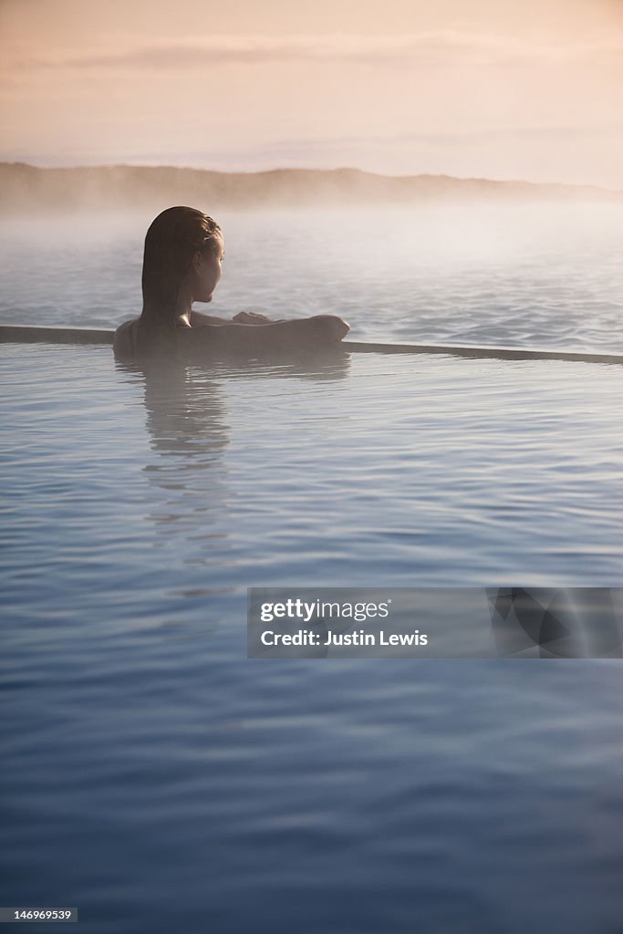 Girl looking out over misty water in hot spring