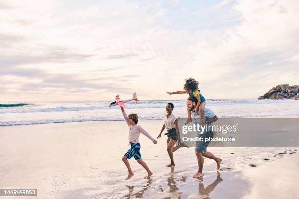 family, running or airplane fun on sunset beach, ocean or sea in freedom holiday, energy bonding or playing game. smile, happy or children with flying toys, piggyback or interracial parents by water - mother and child in water at beach stock pictures, royalty-free photos & images