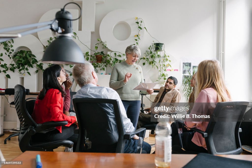 Woman Talking While Surrounded By Colleaguse At The Office