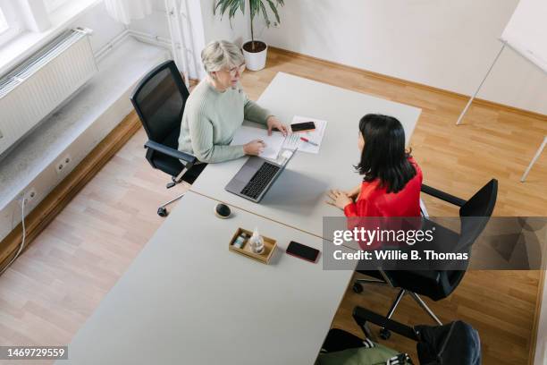 high angle view of businesswoman talking to colleague at her desk - bewerbung stock-fotos und bilder