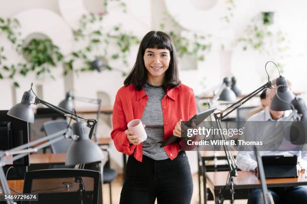 portrait of young businesswoman holding laptop in office - draft portraits stock-fotos und bilder