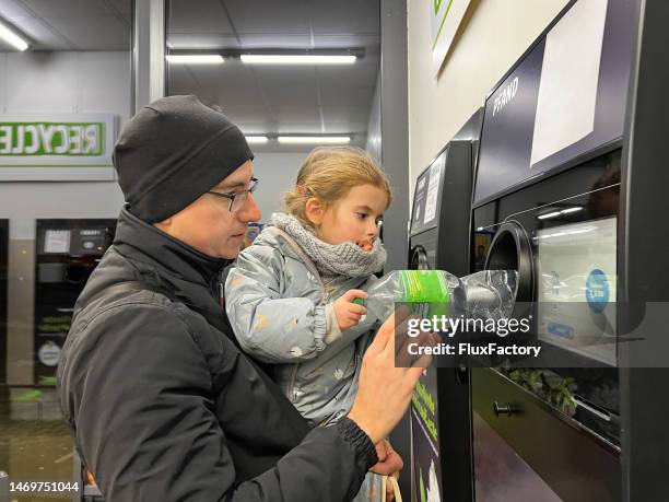 father with daughter, recycling plastic bottle via reverse vending machine - glasbak stockfoto's en -beelden