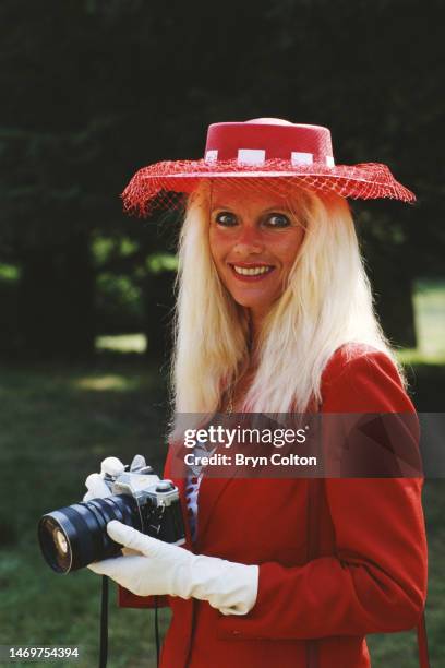 Countess Gunilla von Bismarck wearing a red outfit and holding a camera. She is attending the wedding ceremony of Count Leopold von Bismarck and his...