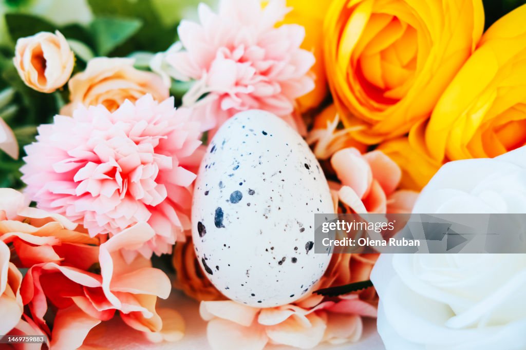 Quail egg among colorful flowers.
