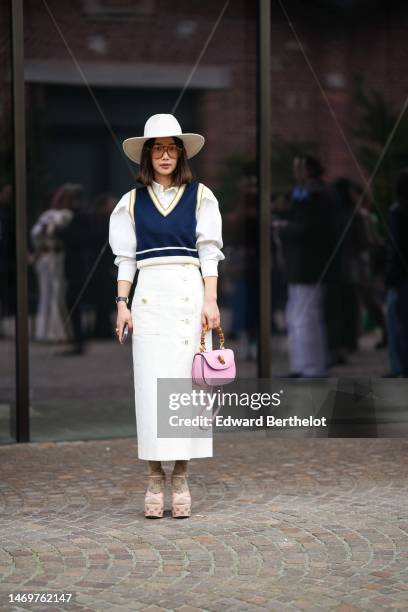 Guest wears a white felt wool hat, orange sunglasses, a white puffy shoulder shirt, a navy blue with white large borders V-neck / sleeveless...