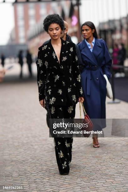 Sharon Alexie wears a black velvet with embroidered gold pattern blazer jacket, matching black velvet with embroidered gold pattern large pants, a...