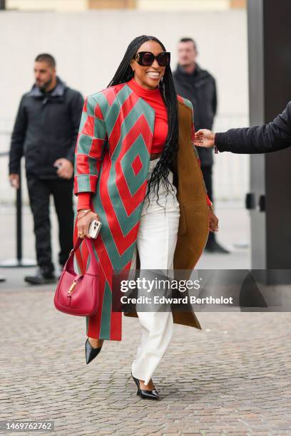 Guest wears black large squared sunglasses from Gucci, gold earrings, a red high neck cropped t-shirt, a camel shiny leather with half green and red...