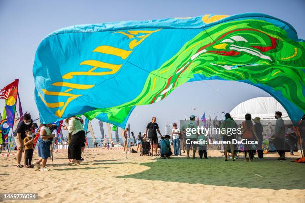 Tourists stand under a giant kite on Central Pattaya Beach during the International Kite on the Beach Festival on February 26, 2023 in Pattaya,...