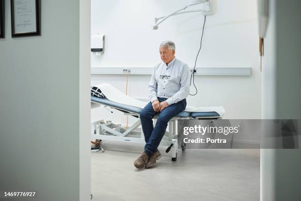 paciente idoso do sexo masculino que visita uma clínica de saúde à espera de médico - sala de exame médico - fotografias e filmes do acervo