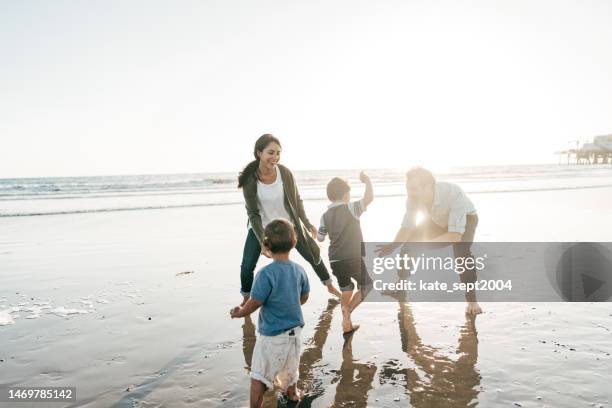 parents playing with kids on the beach - férias de primavera imagens e fotografias de stock