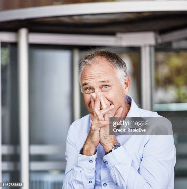 startled and embarrassed-looking businessman looks at the camera as he stands outside office entrance - shameful stock pictures, royalty-free photos & images