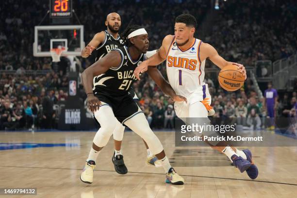 Devin Booker of the Phoenix Suns dribbles the ball against Jrue Holiday of the Milwaukee Bucks in the first half of the game at Fiserv Forum on...
