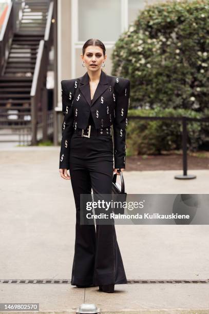 Guest is seen wearing black wide pants and black cropped jacket with metal letter S decorations outside the Annakiki show during the Milan Fashion...