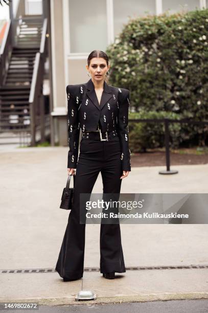 Guest is seen wearing black wide pants and black cropped jacket with mettal letter S decorations outside the Annakiki show during the Milan Fashion...
