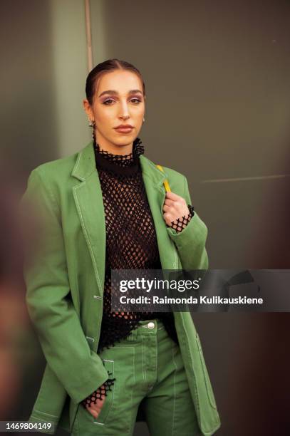 Ginevra Mavilla is seen wearing black leather shoes, a black fishnet shirt, a green denim jacket, and matching green denim cargo pants with pockets...