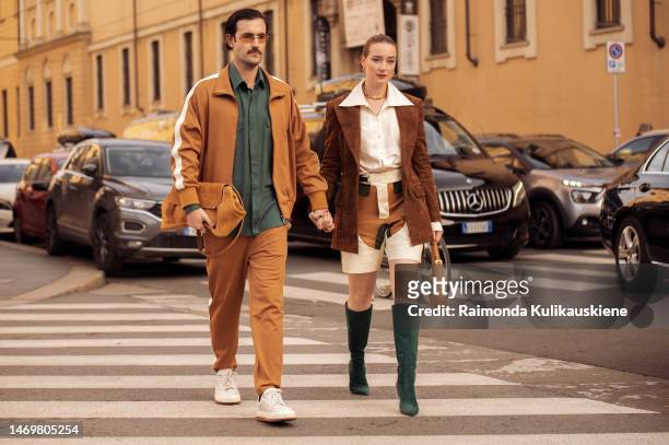 Couple Young Emperors wearing beige track suit, green button shirt, wild leather jacket, shorts with print, white blouse, green boots outside Bally...