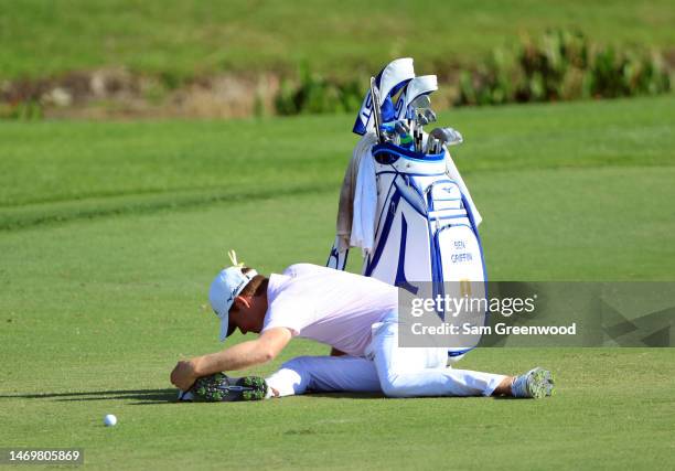 Ben Griffin of the United States stretches while waiting in the fairway to play his second shot on the 16th hole during the final round of The Honda...
