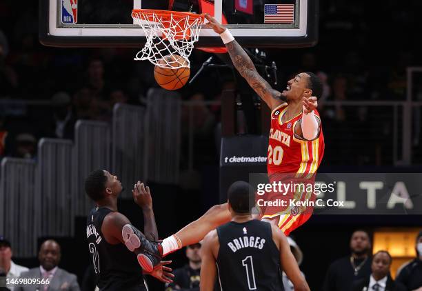 John Collins of the Atlanta Hawks dunks against Dorian Finney-Smith and Mikal Bridges of the Brooklyn Nets during the second quarter at State Farm...