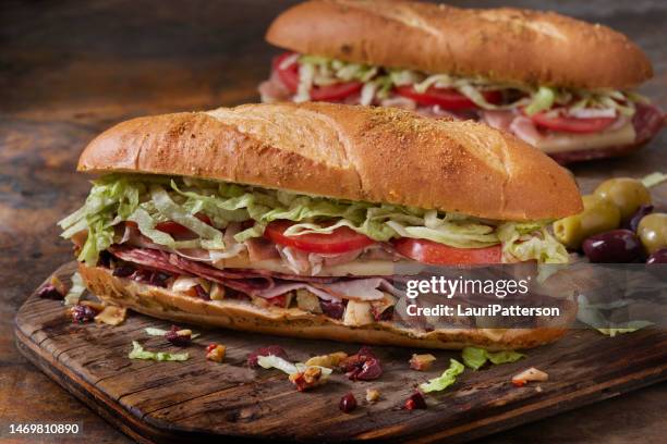 muffuletta, italienisches sandwich mit oliven, gerösteten paprika und artischockenaufstrich - provolone stock-fotos und bilder