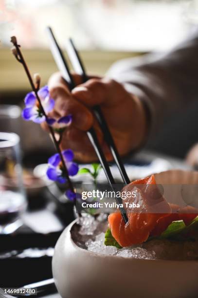 gros plan d’un homme mangeant un sashimi de saumon dans un bar à sushis. - trout stock photos et images de collection