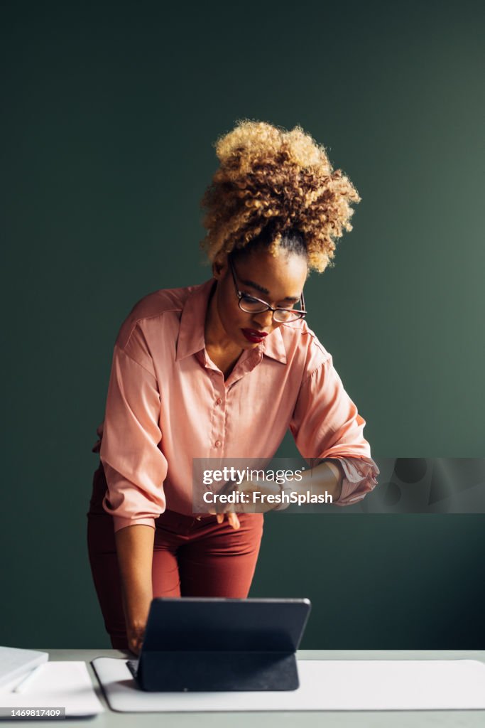 A Serious Beautiful Businesswoman With Blonde Curly Hair Checking Time On Her Smartwatch While Working On Her Tablet