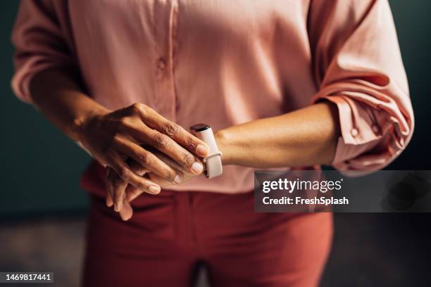 a close up view of an unrecognizable businesswoman checking time on her smartwatch - arm span stockfoto's en -beelden