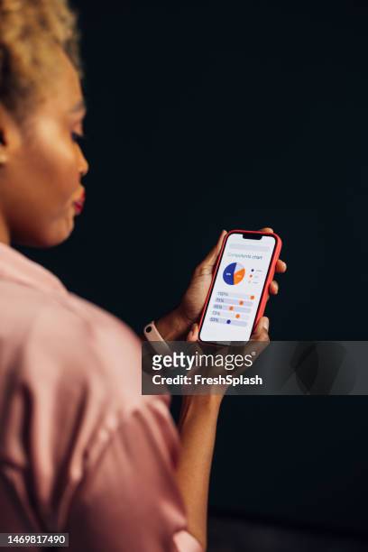 a beautiful businesswoman using her mobile phone while analyzing some charts - female worried mobile imagens e fotografias de stock