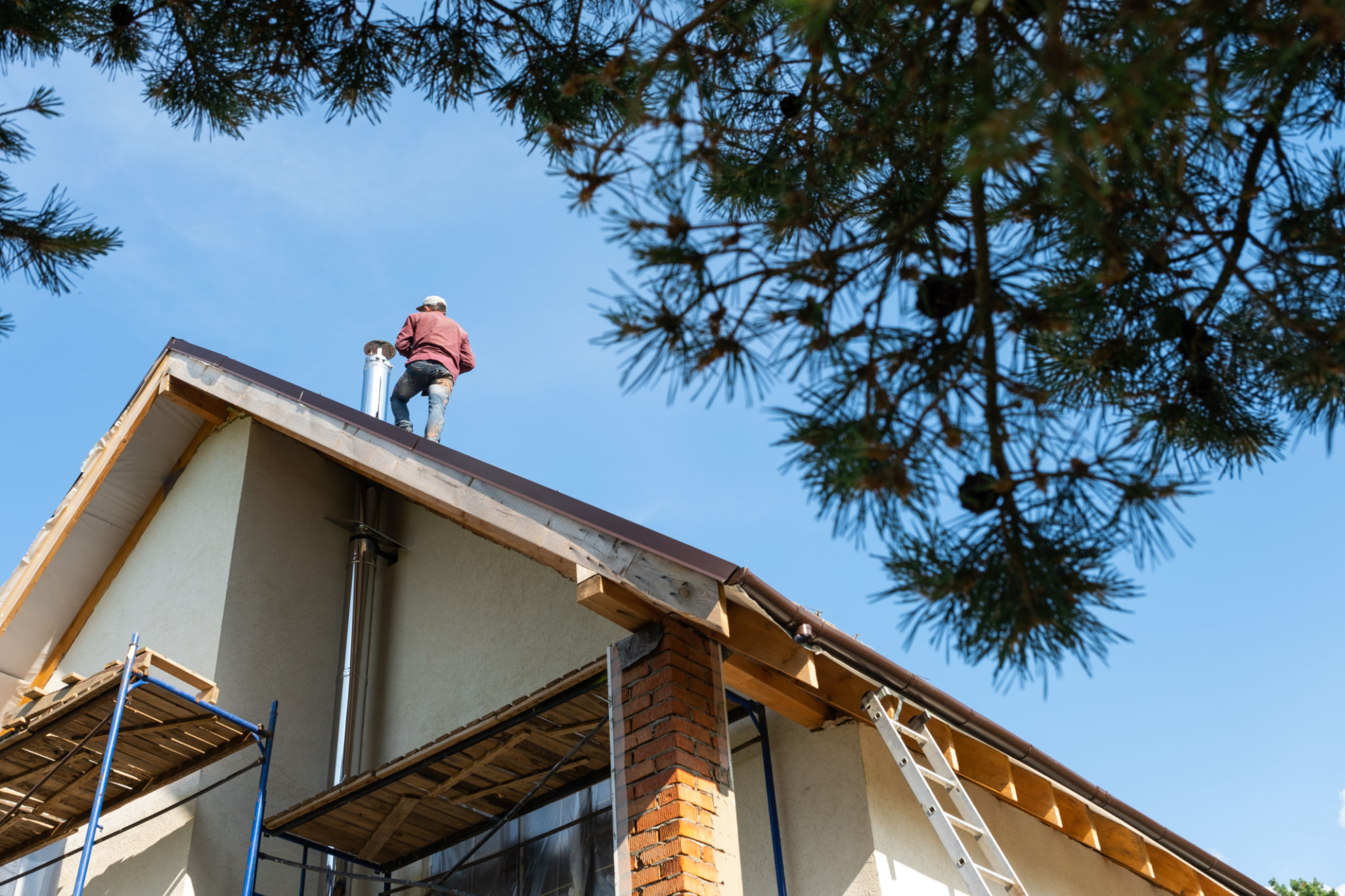 The master for the installation of ventilation pipes and the installation of the chimney of the furnace works on the roof of the house The master for the installation of ventilation pipes and the installation of the chimney of the furnace works on the roof of the house