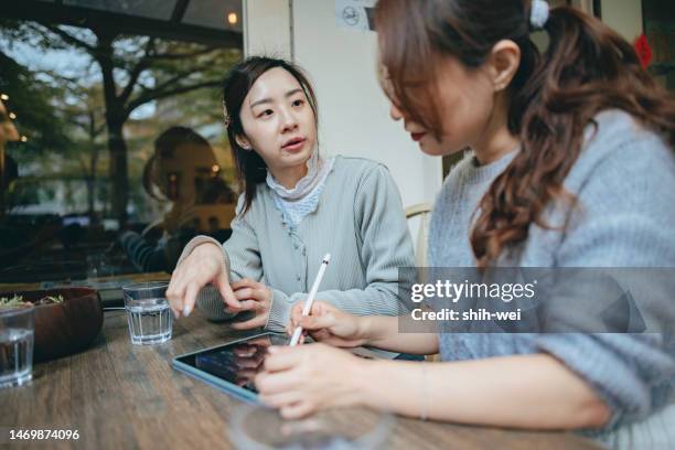 business partners working joyfully together on digital tablet in cafe - infographic day in the life stock pictures, royalty-free photos & images