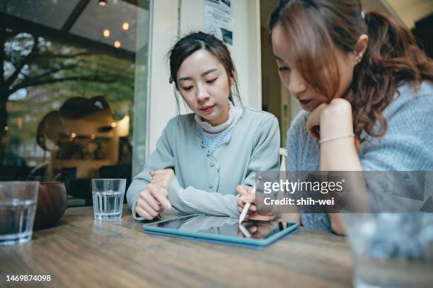 business partners working joyfully together on digital tablet in cafe - infographic day in the life stock pictures, royalty-free photos & images