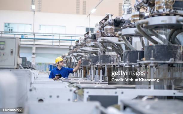 Male worker examining at automated machinery production line at Plastic factory