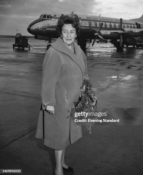 Romanian biologist and physician Ana Aslan standing on the tarmac with a British European Airways aircraft in the background at London Airport, in...