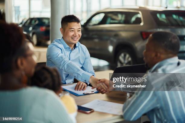 happy chinese car salesperson came to an agreement with his customers in a showroom. - car salesperson stock pictures, royalty-free photos & images