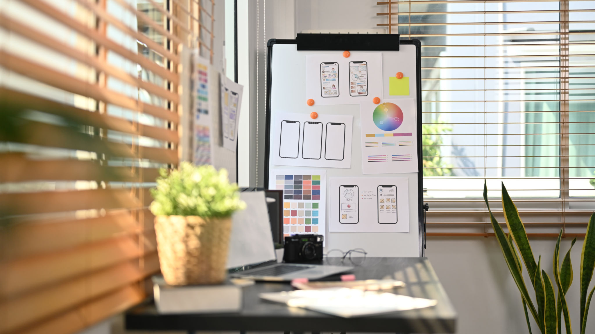 Creative office with laptop, stationery and wireframe sketches of screens for mobile application on a flip board. Creative office with laptop, stationery and wireframe sketches of screens for mobile application on a flip board.