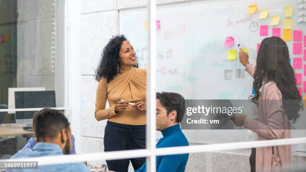 smiling project managers explaining brainstorming technique to colleagues in office meeting - learning agility stock pictures, royalty-free photos & images