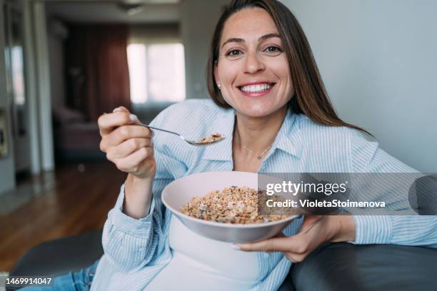 donna incinta che gode di una ciotola di cereali. - avena cereali da colazione foto e immagini stock