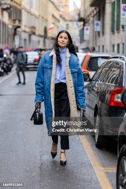 Caroline Issa wears denim shearling coat, black pants, bag, blue button shirt outside Giorgio Armani during the Milan Fashion Week Womenswear...