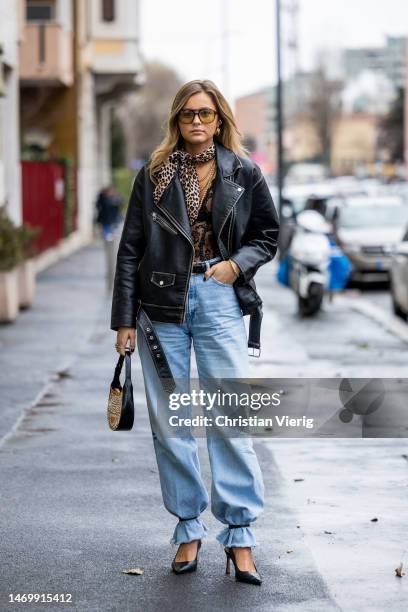 Maxime Moeckl wears leather jacket, denim jeans, pointed heels, bag, animal print scarf outside Annakiki during the Milan Fashion Week Womenswear...