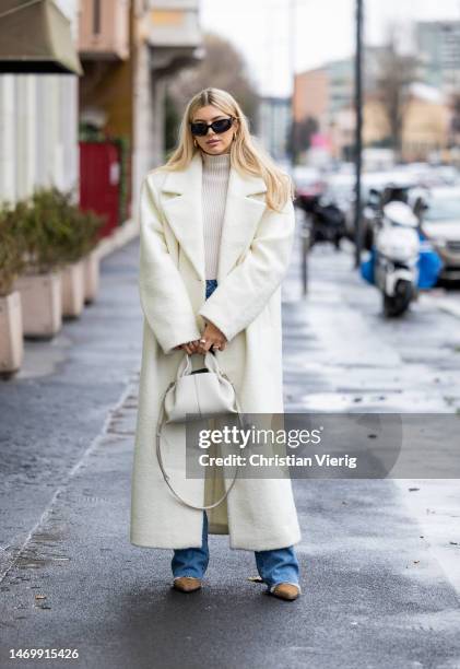 Teresa Jg wears creme white coat, denim jeans, Polene bag, turtleneck outside Annakiki during the Milan Fashion Week Womenswear Fall/Winter 2023/2024...