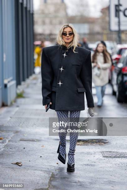 Guest wears wide shoulder jacket, logo print leggings, pointed heels outside Annakiki during the Milan Fashion Week Womenswear Fall/Winter 2023/2024...