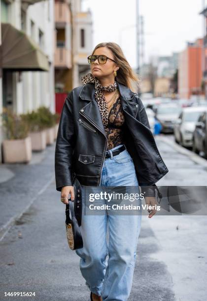 Maxime Moeckl wears leather jacket, denim jeans, pointed heels, bag, animal print scarf outside Annakiki during the Milan Fashion Week Womenswear...