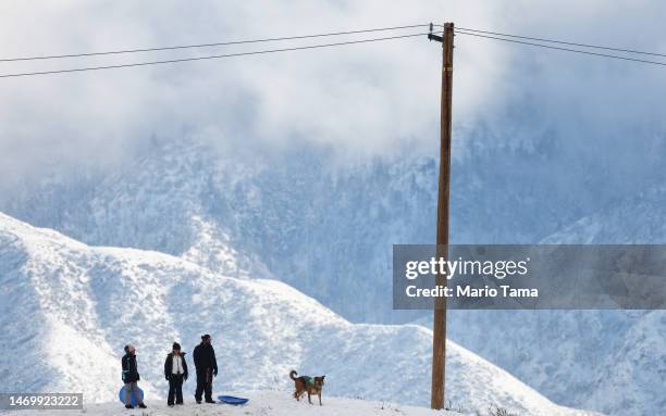 People prepare to sled down a snowy hillside in Los Angeles County on February 26, 2023 near Acton, California. A major storm, which carried a rare...