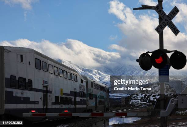 Commuter train passes in front of snow-covered mountains in Los Angeles County on February 26, 2023 near Acton, California. A major storm, which...