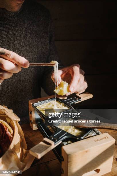 detail of hands melting cheese - schweizer käse stock-fotos und bilder