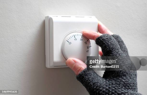 hand adjusting heating thermostat - fingerless gloves stock-fotos und bilder