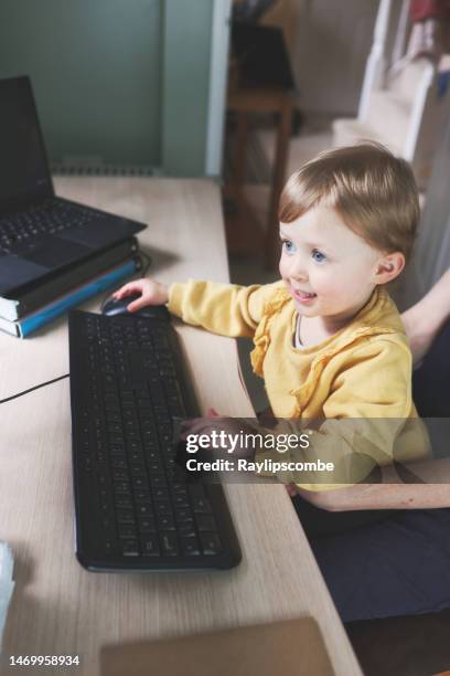 cute 2 year old girl busily working at a home computer - multitasking student stock pictures, royalty-free photos & images