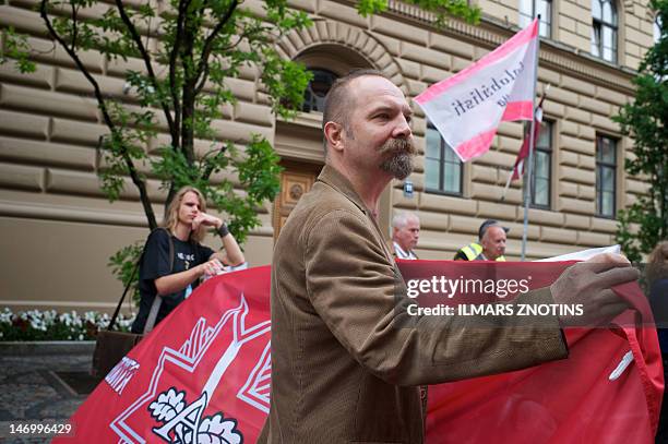 Edvins Puke, one of a dozen protesters, demonstrate against raising the retirement age from 62 to 65 in front of the Latvian parliament building on...