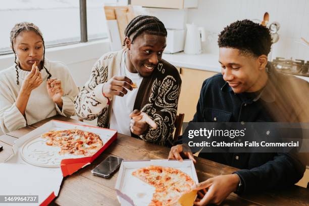 young people enjoy a fresh, delicious pizza, directly from a cardboard pizza box. - pizza restaurant stock pictures, royalty-free photos & images