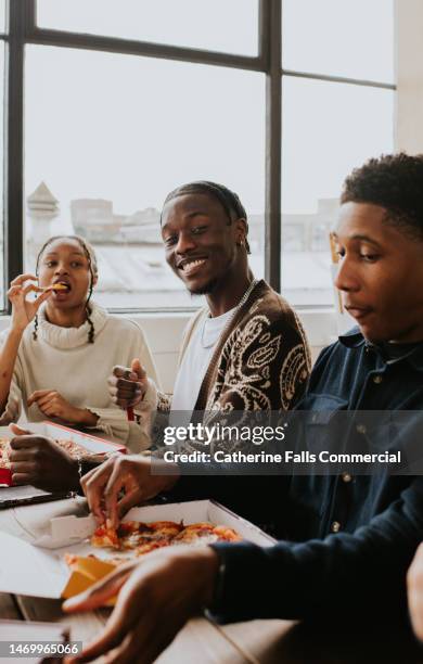 three young people share a pizza together - campus party stockfoto's en -beelden